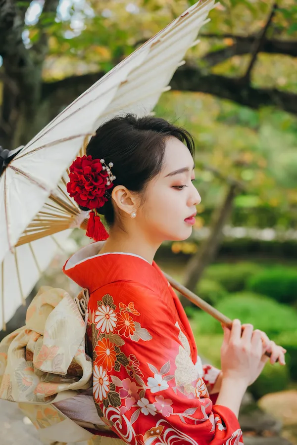 Woman in a red kimono holding a traditional Japanese umbrella at andot kyoto